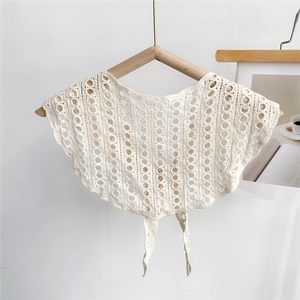 Detailed macro of white hollow-out crochet lace shawl with wavy edges and tie strings