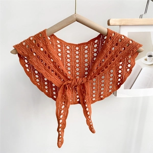 Detail of orange-red knitted lace capelet with hollow circular pattern and front tie