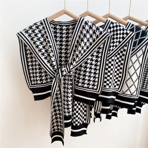 Classic black and white houndstooth knitted shawl shoulder wrap on a wooden hanger