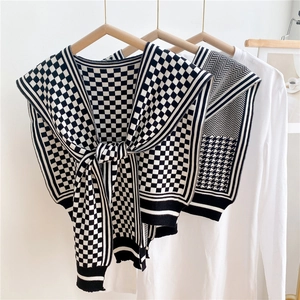 Classic black and white houndstooth knitted shawl wrap on a wooden hanger with white shirt
