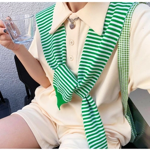 Detail of green striped knit shawl over a beige polo top with waffle texture