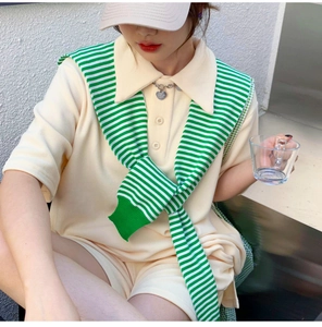Detail of green and white striped knit shawl accessory layered on waffle knit outfit