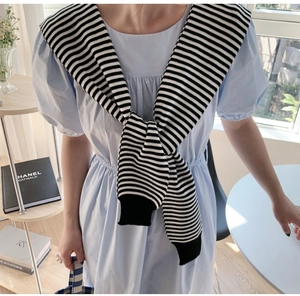 Detail of a black and white striped knitted shawl draped over a blue puff sleeve dress