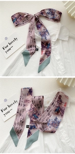 Detail of artistic landscape silk twilly scarf tied as an elegant neck bow on white shirt
