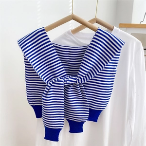 Detail of blue and white striped knit shawl with front knot on a white T-shirt