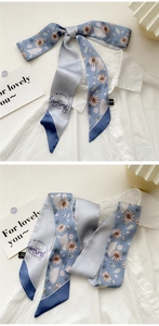 Detail of light blue floral skinny silk scarf with daisy patterns on white shirt collar