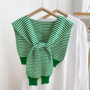 Detail of green and white striped knit shawl accessory with front knot design and soft texture