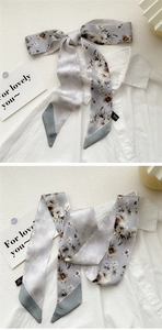 Detailed view of floral silk scarf tied as a bow on white shirt collar with 100% silk texture