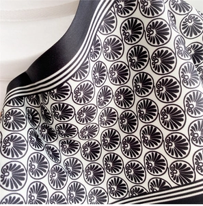 Detailed close-up of a high-quality silk scarf with black and white geometric shell patterns