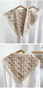 Detail of horsebit chain print on a silky beige shawl draped over a white blouse