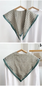 Detail of cream triangle shawl with black geometric patterns and green border