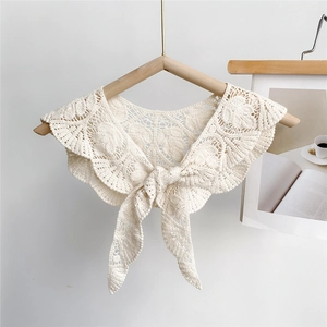Detail of hollow leaf lace texture on beige crochet shawl with front bow tie closure