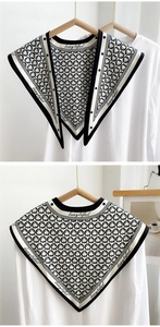 Detail view of knitted black and white triangle shawl with geometric chain pattern and text