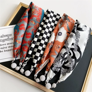 Five silk scarves with magnetic crystal pendants on a luxury black jewelry display tray