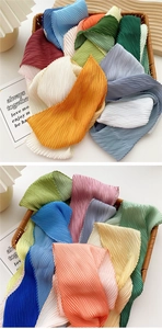 Detailed close-up of colorful pleated silk scarves showing fine accordion texture in a basket