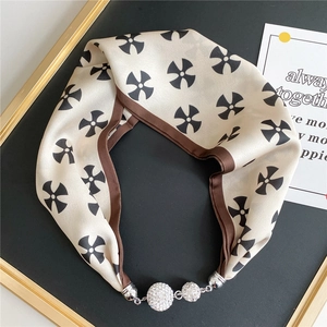 Detail of silk-feel scarf necklace featuring brown geometric pattern and crystal magnetic clasp