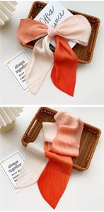 Detail of pleated silk scarf showing orange, pink and beige three-color gradient splice