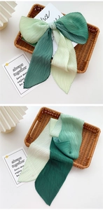 Detail of pleated silk scarf showing gradient shades of green and fine accordion texture