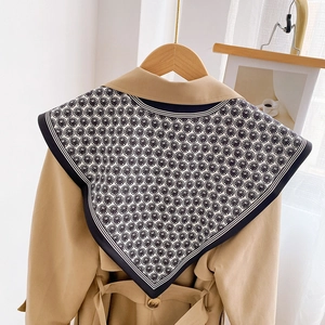 Elegant black and white geometric print silk scarf styled on a khaki trench coat