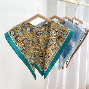 Various patterned silk-feel triangle scarves hanging on hangers for autumn and winter