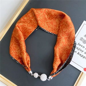 Detail view of orange floral silk scarf with sparkling rhinestone magnetic clasp closure
