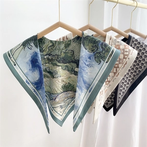 Three elegant patterned silk scarves hanging on a wooden hanger with aesthetic prints