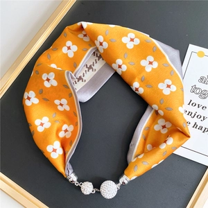 Detail of a bright yellow floral silk scarf featuring a luxury sparkling rhinestone buckle