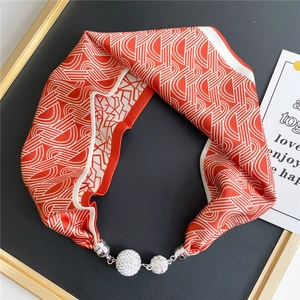 Close-up of geometric silk scarf with magnetic silver buckle and rhinestone spheres