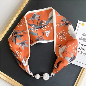 Detail of silk scarf necklace with orange floral bee print and sparkling crystal buckle