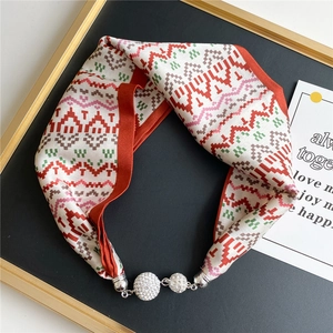 Macro detail of geometric print silk scarf featuring rhinestone spheres and silver magnetic clasp