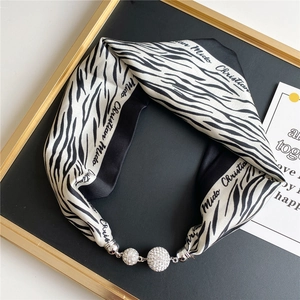 Detail of zebra print silk scarf with luxury silver rhinestone magnetic ball buckle
