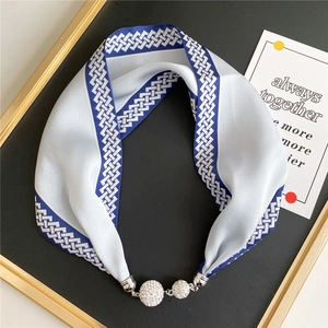 Close-up of silk scarf necklace with blue geometric patterns and luxury rhinestone buckle