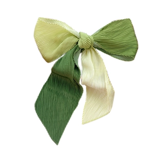 Pleated gradient green bow hair accessory with ombre fabric texture on white background