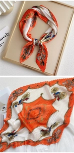 Detailed view of pleated silk scarf with orange horse carriage print and chain patterns