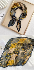 Detail of pleated silk scarf with yellow floral and navy abstract bird print patterns