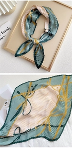 Detailed view of pleated silk scarf featuring green and yellow geometric patterns