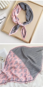 Detailed view of pink and black pleated silk scarf with horse and monogram pattern