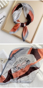 Close-up of pleated silk scarf with orange and grey geometric fish scale pattern
