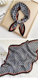 Detail of pleated silk scarf featuring black and white geometric patterns with striped edges