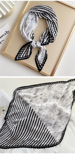 Detail of pleated silk scarf featuring black white stripes and floral print textures