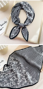 Detail of pleated black and white paisley silk scarf with zigzag edges and geometric print