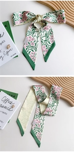 Detail of floral twilly silk scarf featuring green leaves and pink daisies print