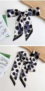 Detailed close-up of polka dot and rose pattern silk scarf tied in a bow on a white desk