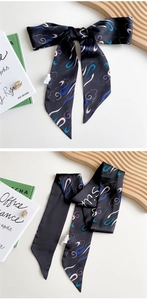 Close-up of black silk scarf with retro cloud pattern on a minimal tray display