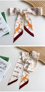 Detail of elegant skinny scarf with fox print and artistic lettering on a wooden tray