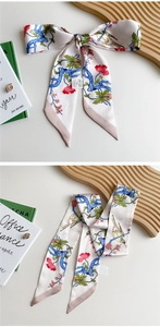 Detail of floral and bird print twilly scarf with pink pointed ends on white table
