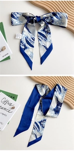 Detail of a narrow silk scarf with blue and white wave prints and pointed ends