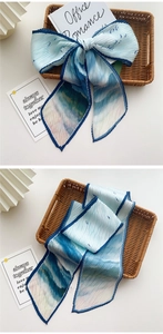 Détail d'un foulard plissé en soie dégradé bleu et blanc avec motifs vagues et oiseaux