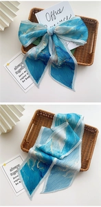 Détail d'un foulard plissé bleu avec motifs de marbre doré sur un élégant fond blanc épuré