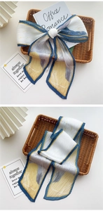Détail d'un foulard en soie plissé aux motifs jaune et bleu noué en nœud élégant